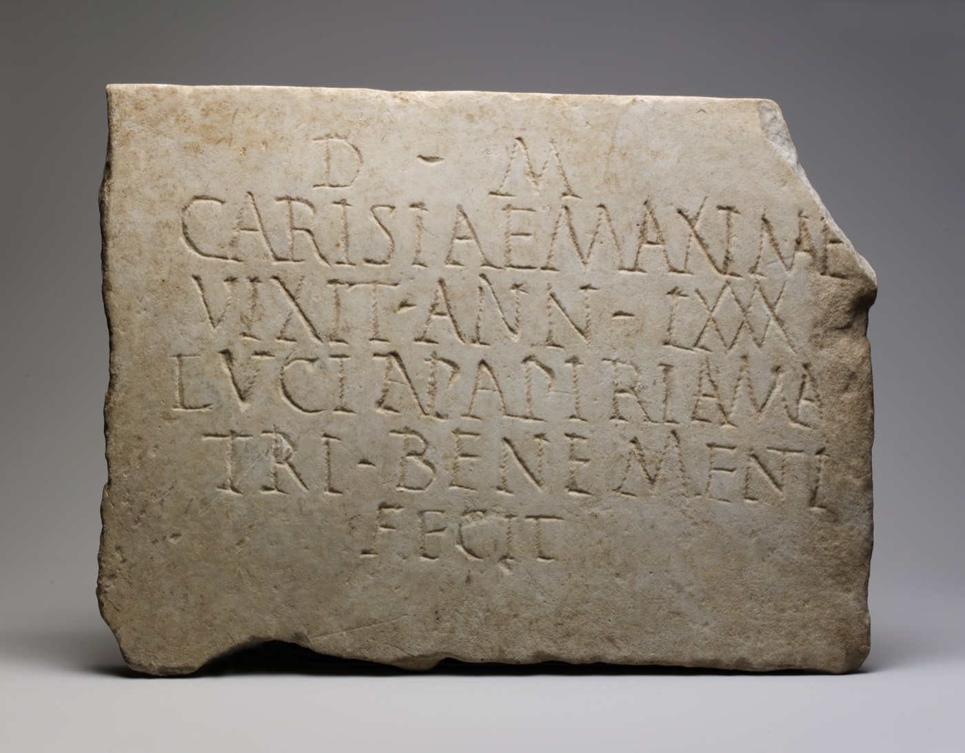 A rectangular marble slab carved with six lines of Latin in capital letters. Words run together with only occasional raised dots between them, several are abbreviated, and the right edge is broken away mid-line.